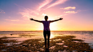 Silhouette of young woman doing yoga on the beach